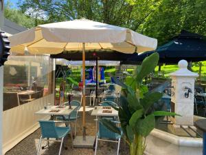 un patio con mesas y sillas bajo una sombrilla en La Trinite en Saint Firmin