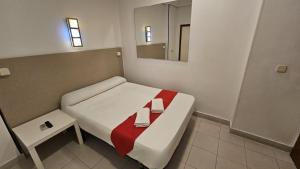 Habitación pequeña con cama y espejo. en Hostal Las Vegas, en Madrid