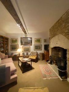 a living room with a stone fireplace and a couch at Market Place Cottage, Tetbury, Cotswolds Grade II Central location in Tetbury