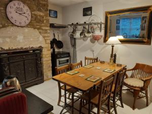 Market Place Cottage, Tetbury, Cotswolds Grade II Central location في تيتبري: غرفة طعام مع طاولة وساعة على الحائط