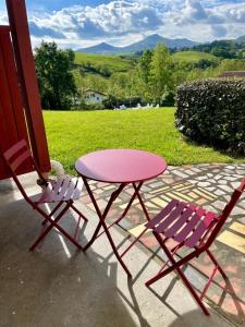 einen rosa Tisch und zwei Stühle auf einer Veranda in der Unterkunft MEHATCHE Piscine Vue Montagnes in Souraïde