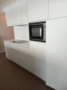 a kitchen with white cabinets and a microwave at The Loft 2.0 in De Panne