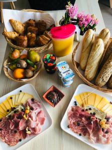una mesa con platos de comida y cestas de pan en Le gîte du faubourg, en Sautour