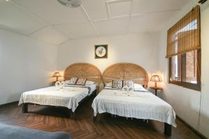 two beds in a room with white walls and wooden floors at Ohana House @ 31 Jawa in Melaka
