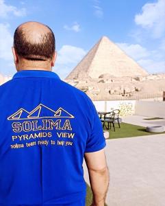 a man in a blue shirt looking at the pyramids at Solima Pyramids View in Cairo