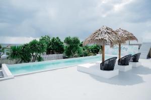 a swimming pool with chairs and a straw umbrella at Woywoy Paradise in Bira