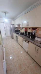 uma grande cozinha com armários brancos e piso em azulejo em Spacieux appartement au centre-ville de Tanger em Tânger