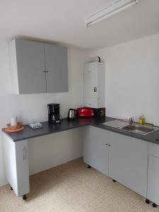 a kitchen with white cabinets and a black counter top at Petite maison étape Loire à vélo ou Compostelle in Mosnes