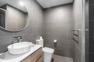 ein Badezimmer mit einem Waschbecken, einem WC und einem Spiegel in der Unterkunft O‘Connor 3 bedroom Townhouse in Canberra in Canberra