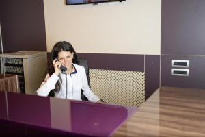 Hotel Story في تارغو جيو: امرأة جالسة في مكتب تتحدث على الهاتف الخلوي