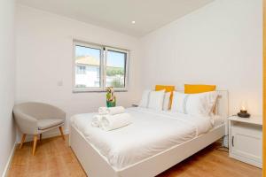ein weißes Schlafzimmer mit einem weißen Bett und einem Stuhl in der Unterkunft Caparica Dream Vila in Costa da Caparica