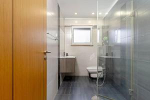 ein Badezimmer mit Toilette und Glasdusche in der Unterkunft Caparica Dream Vila in Costa da Caparica + 40 Fotos