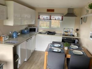 a kitchen with white cabinets and a table with chairs at Margaret Ann Chalet in Seaton