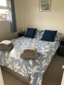 een slaapkamer met een bed met blauwe kussens bij Margaret Ann Chalet in Seaton