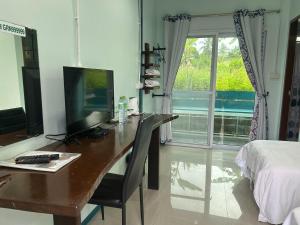 a desk with a computer on it in a bedroom at Green Country Park Resort in Ban Tha Mak