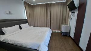 um quarto com uma cama branca e uma televisão em Green Country Park Resort em Ban Tha Mak
