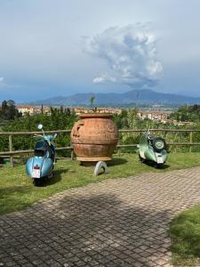 deux scooters et un vase assis à côté d'une clôture dans l'établissement Residence Montevecchio, à Montopoli in Val dʼArno