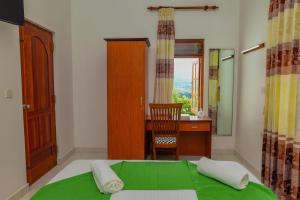 a bedroom with a green bed with a desk and a chair at Siyonra Bungalow in Matale