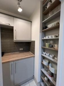 una cocina con armarios blancos, fregadero y estanterías en Lovely Home in Kimmage, Dublin en Dublín