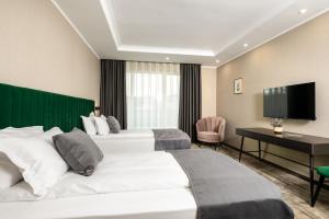 a hotel room with two beds and a flat screen tv at Empire Balneo and Spa Hotel in Hisarya