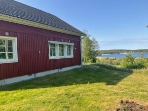 a red house with a yard next to a lake at Villa med sjöutsikt in Fors