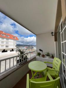 a balcony with a green table and chairs and a view at Piso Azalea Combarro in Combarro