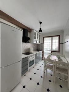 cocina con electrodomésticos blancos y suelo blanco y negro en Piso Azalea Combarro, en Combarro