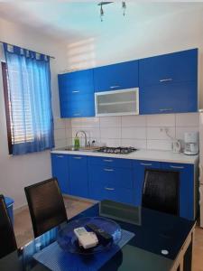 a kitchen with blue cabinets and a table with chairs at Kuća NIKA in Tribunj