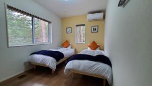 2 Betten in einem Zimmer mit Fenster in der Unterkunft Compass Duo in Karuizawa