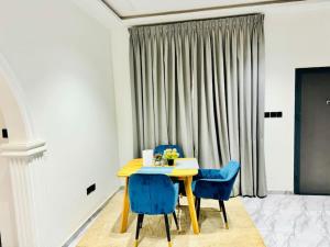 a dining room with a table and two blue chairs at Executive 2bedroom House in Tema