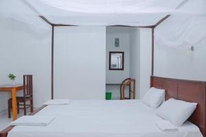 1 dormitorio con 2 camas, mesa y sillas en Ocean Breeze Resort, en Pottuvil