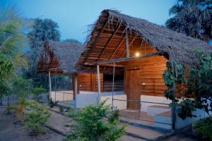 una pequeña casa de madera con techo de paja en Ocean Breeze Resort, en Pottuvil