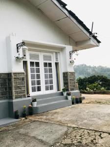 een wit huis met een raam en een aantal planten bij WHITE ROSE VILLA in Kandy