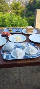 een houten tafel met witte borden en kommen erop bij WHITE ROSE VILLA in Kandy