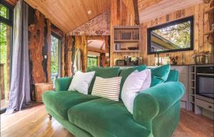 a green couch in a living room with wooden walls at Unique Secluded Romantic Treehouse in Cornwall, sleeps 2 in Looe