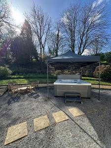 a hot tub under an umbrella next to a bench at Cowslip Cottage Serenity with Jacuzzi in Saundersfoot