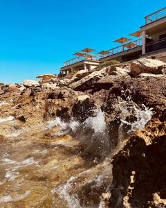 a building on top of a rocky mountain with a waterfall at Hotel Plein Large in Bandol