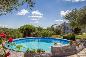 a swimming pool in a yard with flowers at Classical Villa Anta in Agios Ioannis