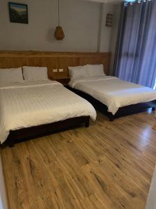 Sapa Aroma Hotel في سابا: سريرين في غرفة ذات أرضيات خشبية