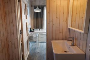 a bathroom with a sink and a table with chairs at Brouwersdam Stay in Ouddorp