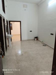 an empty room with a white wall and a tile floor at Kailash home in Deoghar