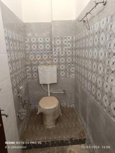 a bathroom with a toilet and a tiled wall at Kailash home in Deoghar