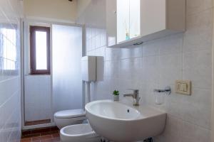 La salle de bains blanche est pourvue d'un lavabo et de toilettes. dans l'établissement Residence Montevecchio, à Montopoli in Val dʼArno