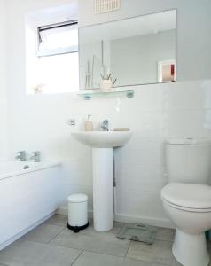 a white bathroom with a sink and a toilet at House with free parking and large garden in Wyke Regis