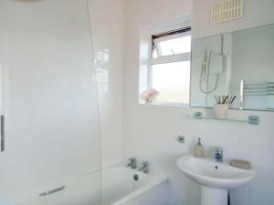 a white bathroom with a sink and a mirror at House with free parking and large garden in Wyke Regis