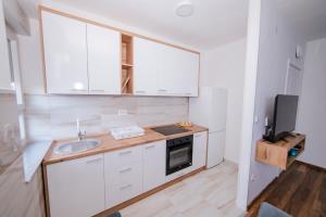 a kitchen with white cabinets and a sink and a television at Apartman Neca Trebinje in Trebinje