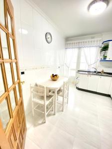 cocina blanca con mesa blanca y sillas en Apartamento Rivela, en Burela de Cabo