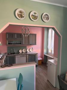 Una pequeña cocina con paredes rosas y verdes. en Thea House, en Casale Monferrato