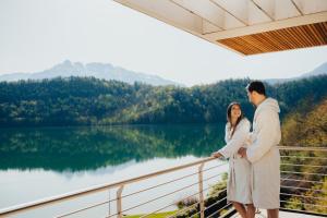 mężczyzna i kobieta stojący na balkonie z widokiem na jezioro w obiekcie Parc Hotel Du Lac w mieście Levico Terme