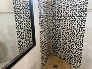 Nianing的住宿－Le teranga royale lodge，配有黑色和白色图案的淋浴帘的淋浴